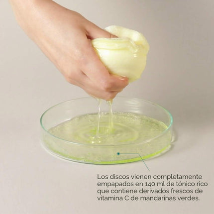 Almohadillas de tóner de mandarina verde aplicación sobre el rostro durante la rutina facial.